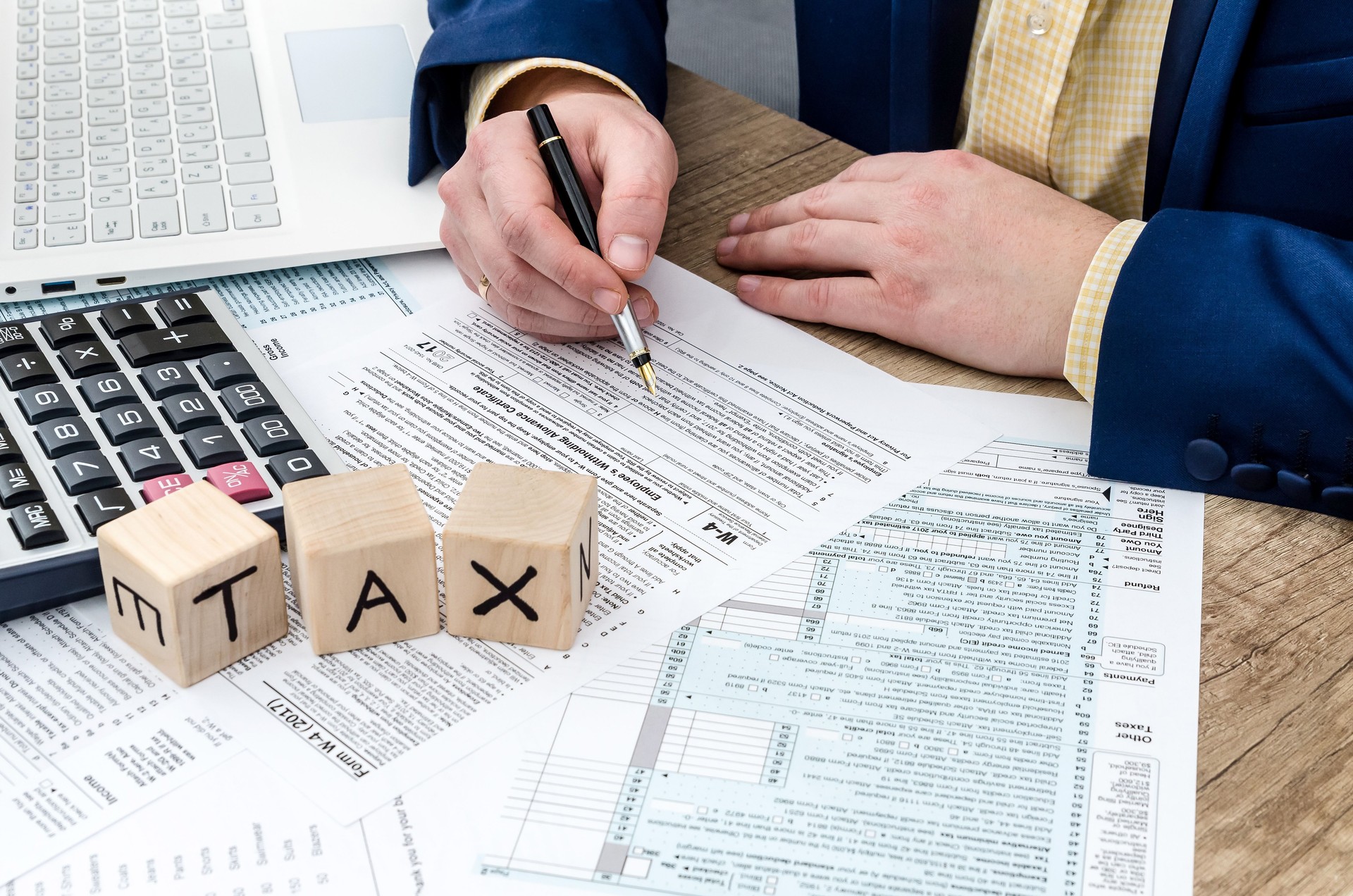 Businessman  filling W-4 form with pen, calculator and pc